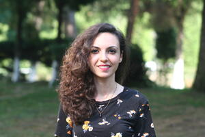 Ceyda Cekmeci stands in front of a small grove of trees.